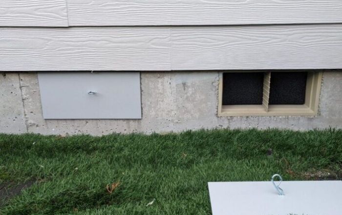 House foundation vent covers on grassy ground.